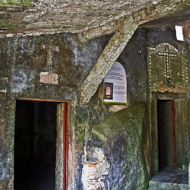 A low cork-lined doorway and cell cut into the rock