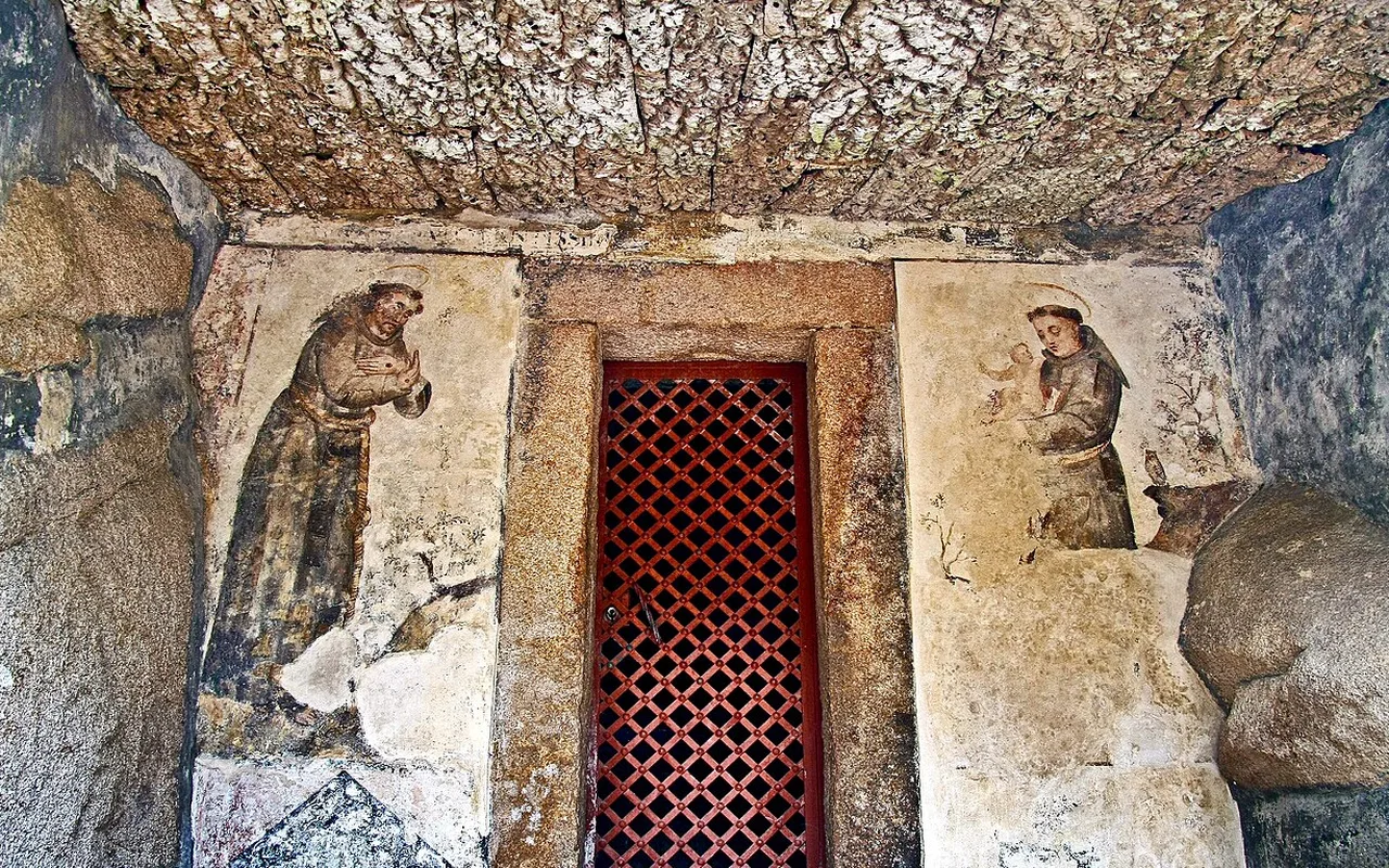 A carved rock doorway with a red lattice grille